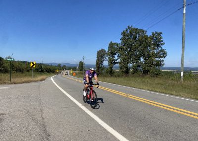Cycling In Houston - NWCC Recent Activities Gallery 186 Cyclist riding on scenic rural road with trees and mountains in the background for Northwest Cycling Club SEO.