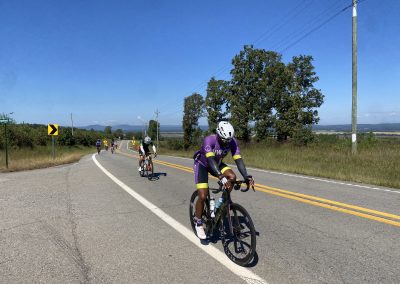 Cycling In Houston - NWCC Recent Activities Gallery 185 Cyclists riding on scenic rural road with mountains in the background, promoting Northwest Cycling Club.