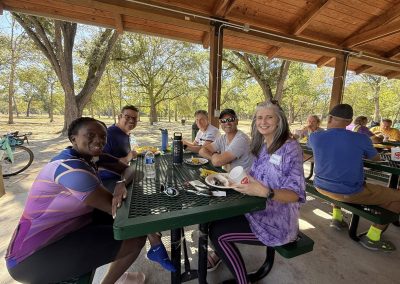 Cycling In Houston - NWCC Recent Activities Gallery 152 Happy cyclists enjoying a meal during an outdoor riding event at Northwest Cycling Club, surrounded by scenic park views.