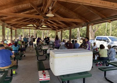 Cycling In Houston - NWCC Recent Activities Gallery 139 Outdoor picnic area at Northwest Cycling Club event with cyclists, families, and a scenic wooded background.