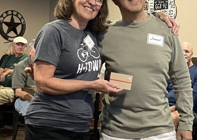 Cycling In Houston - NWCC Recent Activities Gallery 119 Smiling woman in Northwest Cycling Club shirt presenting award to man at bike community event.