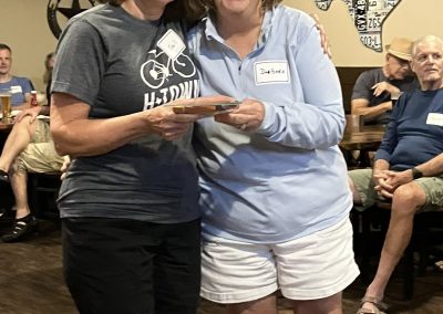Cycling In Houston - NWCC Recent Activities Gallery 118 1. Women at Northwest Cycling Club event, smiling, holding award, indoor gathering, cycling community.