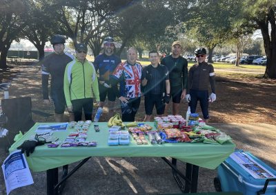 Cycling In Houston - NWCC Recent Activities Gallery 107 Cycling group at Northwest Cycling Club community event with refreshment table and outdoor park setting.