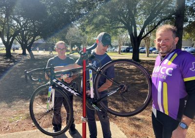 Cycling In Houston - NWCC Recent Activities Gallery 105 Bike wheel being mounted on a stand at Northwest Cycling Club event in Houston, outdoor cycling with riders and volunteers.