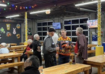 Cycling In Houston - NWCC Recent Activities Gallery 63 Outdoor social gathering at Northwest Cycling Club event in a brewery-like setting with wooden tables.