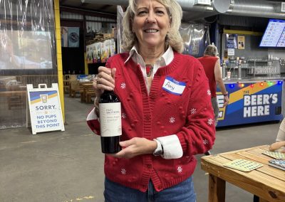 Cycling In Houston - NWCC Recent Activities Gallery 56 Festive woman with reindeer antlers holding a bottle of wine at Northwest Cycling Club's holiday event.