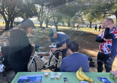 Cycling In Houston - NWCC Recent Activities Gallery 106 Man working on a White Trek bicycle during a Northwest Cycling Club event in Zube Park.