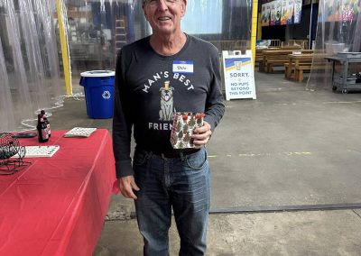 Cycling In Houston - NWCC Recent Activities Gallery 45 Friendly man at Northwest Cycling Club event holding a gift box, smiling in a casual indoor setting.