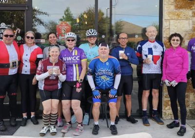 Cycling In Houston - NWCC Recent Activities Gallery 41 Group of cyclists in NWCC Houston cycling club gear outside cafe.